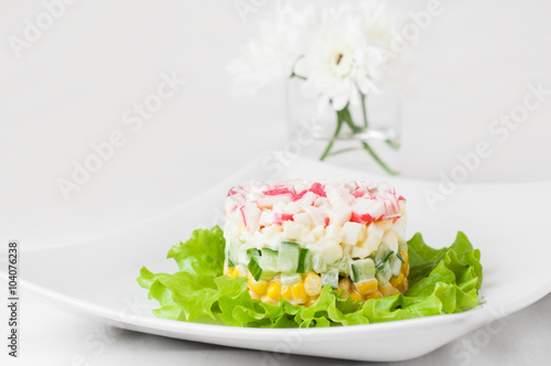Layered crab sticks salad on lettuce leaves