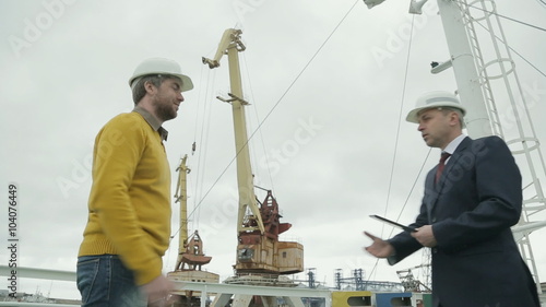 Discussion of a major business project by two businessmen on port