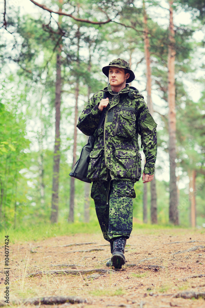 Obraz premium young soldier or hunter with gun in forest