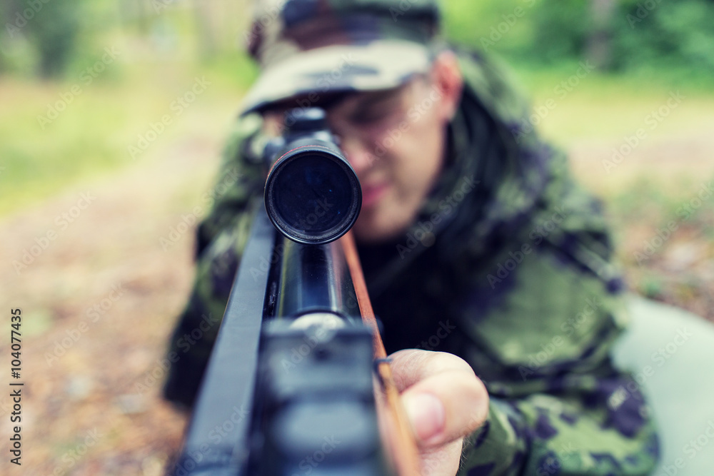 Fototapeta premium close up of soldier or hunter with gun in forest