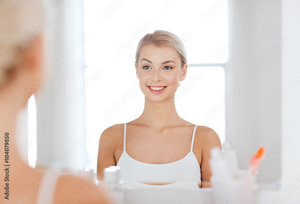 happy young woman looking to mirror at bathroom happy young woman looking to mirror at bathroom