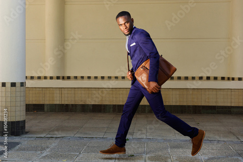Young businessman running on city street