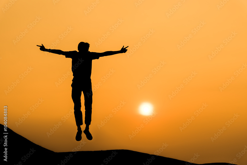 Silhouette of man in happy jump on orange sunset sky