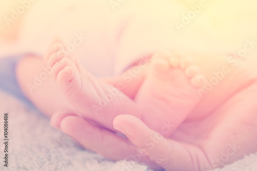 Newborn baby feet on mother hand in warm tone, vintage picture s