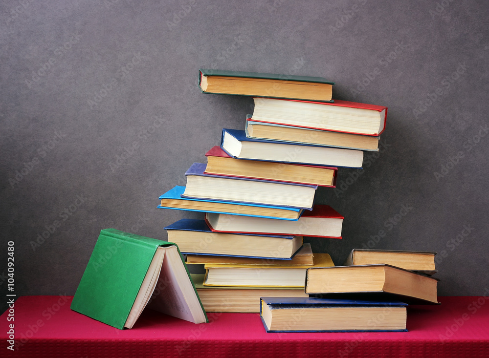 A stack of books on the table with a red tablecloth. A stack of books on the table with a red tablecloth.