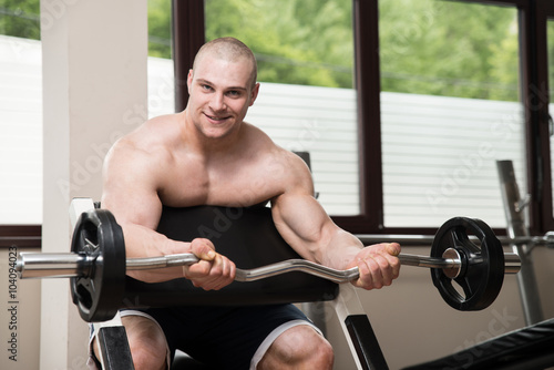 Man In The Gym Exercising Biceps With Barbell