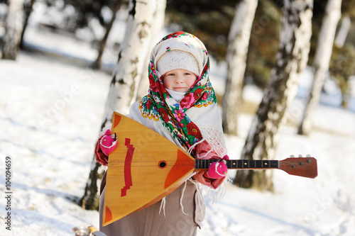 baby girl in a headscarf in the Russian style, with a balalaika