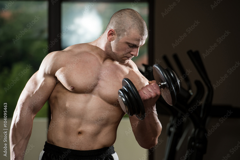 Man In The Gym Exercising Biceps With Dumbbells
