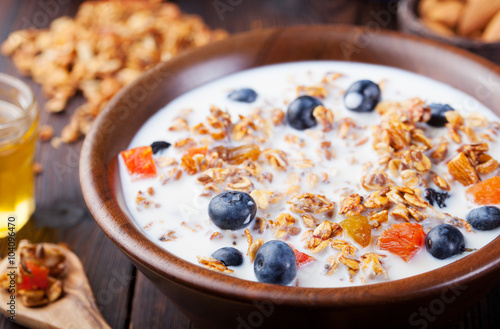 Healthy breakfast. Fresh granola, muesli with berries, honey and milk in a wooden bowl Wooden background