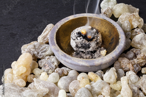 Frankincense burning on a hot coal. Frankincense is an aromatic resin, used for religious rites, incense and perfumes. photo