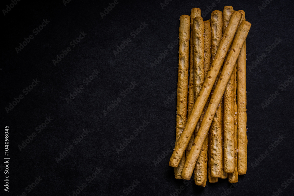 Bread sticks with salt and herbs on dark board