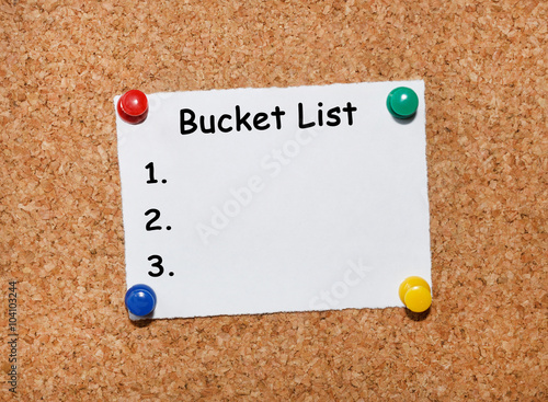 The phrase Bucket list typed on a white piece of note paper and pinned to a cork notice board