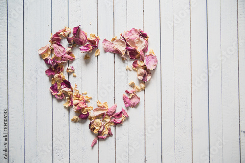 Vintage heart made of dried petals on wooden white background photo