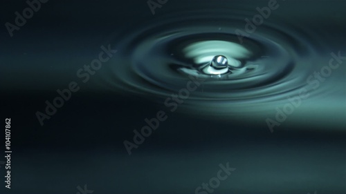 Peaceful Water Drop - A solitary drop of water falls and melts into a pure water surface.