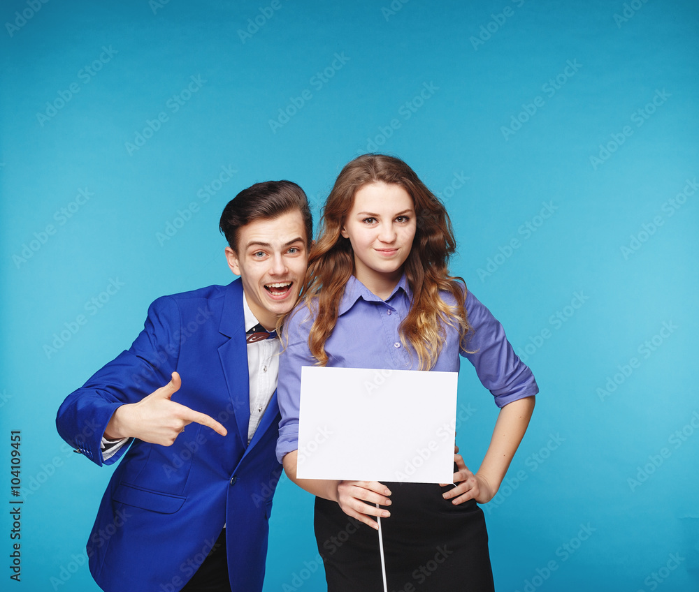 Smiling hipster couple in the jeans and jacket with the sheet in the studio Smiling hipster couple in the jeans and jacket with the sheet in the studio