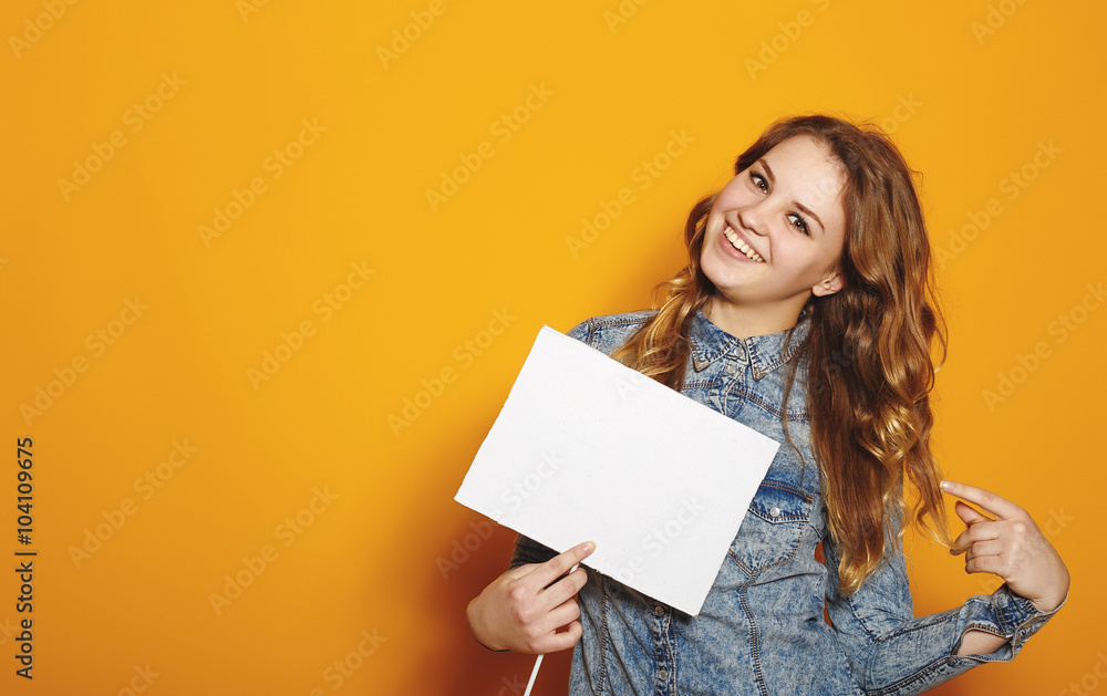 Smiling hipster girl in the jeans with the sheet in the studio Smiling hipster girl in the jeans with the sheet in the studio