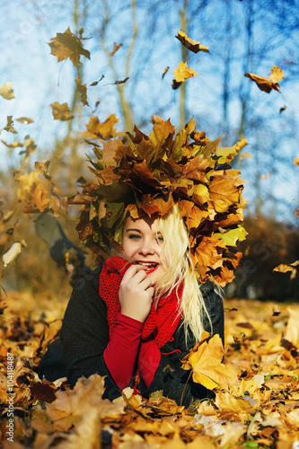 High fashion blonde girl with the red lips in the wreath of leaves and in the fallen leaves in the park outdoor