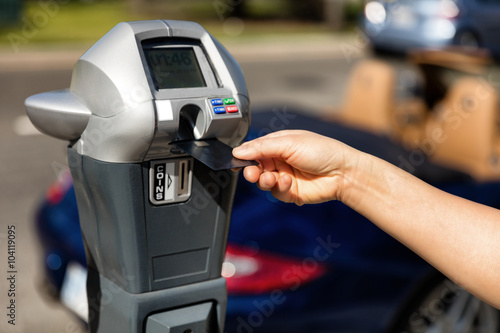 Hand putting credit card into parking meter for time