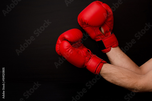 Hand in red boxing gloves in the corner of the frame on a black background, empty space © somemeans