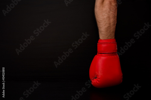 Two hands in red boxing gloves in the side of the frame on a black background,  empty space © somemeans