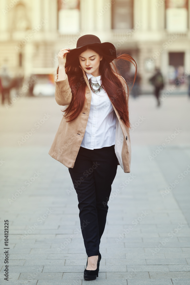 Full body portrait of young beautiful lady wearing stylish classic clothes walking at street of the old city. Girl looking down. Plus size model. Female fashion concept. Toned Stock Photo Adobe