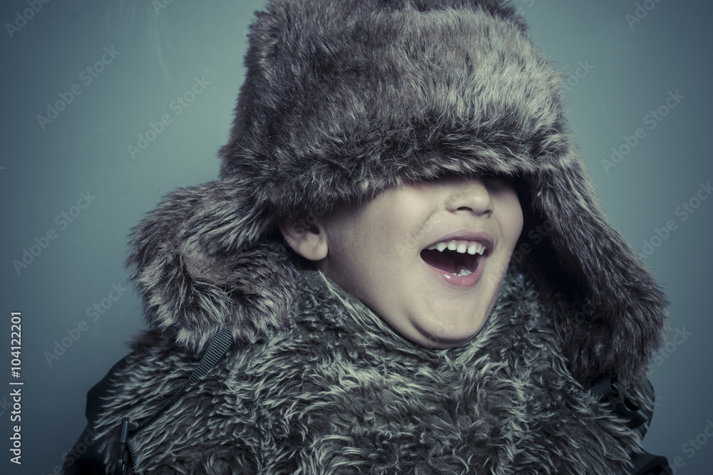 Funny child with fur hat and winter coat, cold concept and storm Funny child with fur hat and winter coat, cold concept and storm