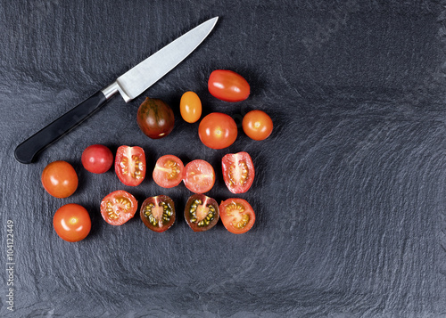 Colorful mixed small tomatoes and cutting knife on natural black