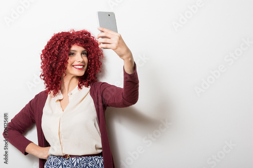 Curly redhead businesswoman taking a selfie on smartphone