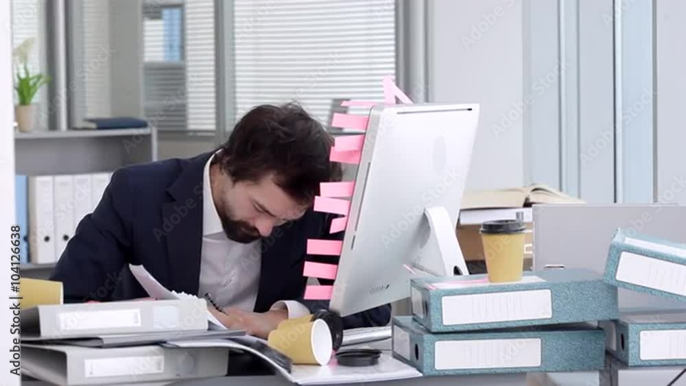 Too Many Task For Me/Businessman sits on a workplace beside a computer. He's in a bad mood, he is angry and embarrassed