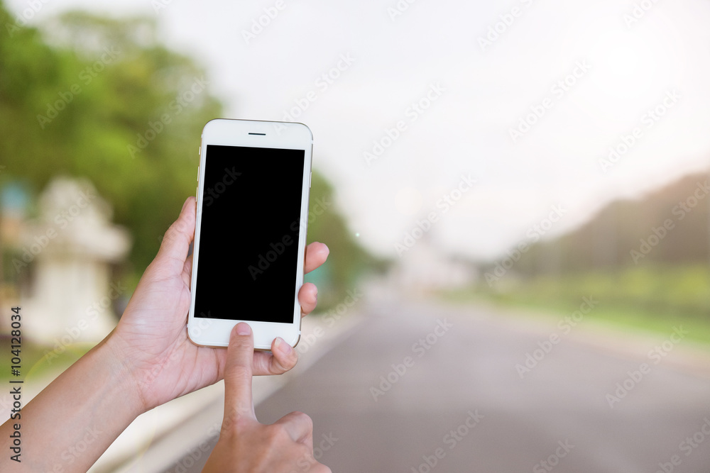 Hands woman are holding touch screen smart phone,tablet on blurred road nature background.