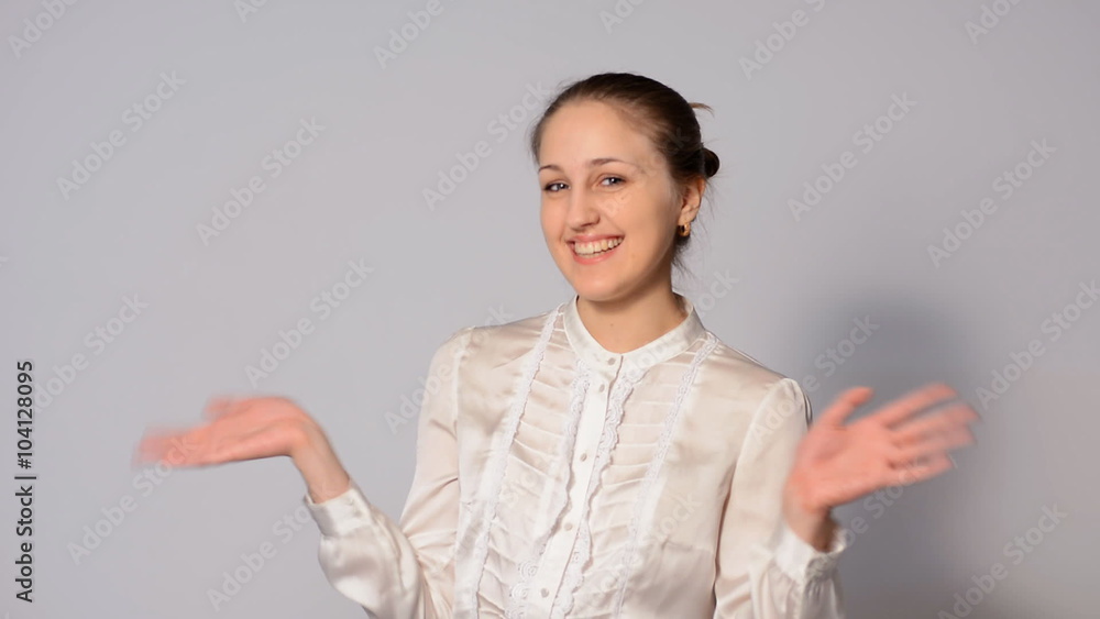 Cheerful girl waving her arms. Young business woman smiling in a white blouse with the collected hair in a bun Cheerful girl waving her arms. Young business woman smiling in a white blouse with the collected hair in a bun