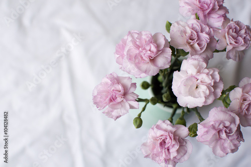 High angle view of pink carnations in a green vase on a white tablecloth © Natalie Board