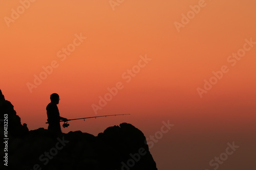 Fisherman in silhouette with sunset
