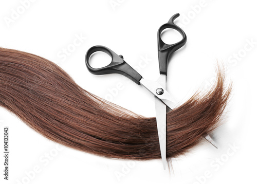 Hairdresser's scissors with strand of dark brown hair, isolated on white