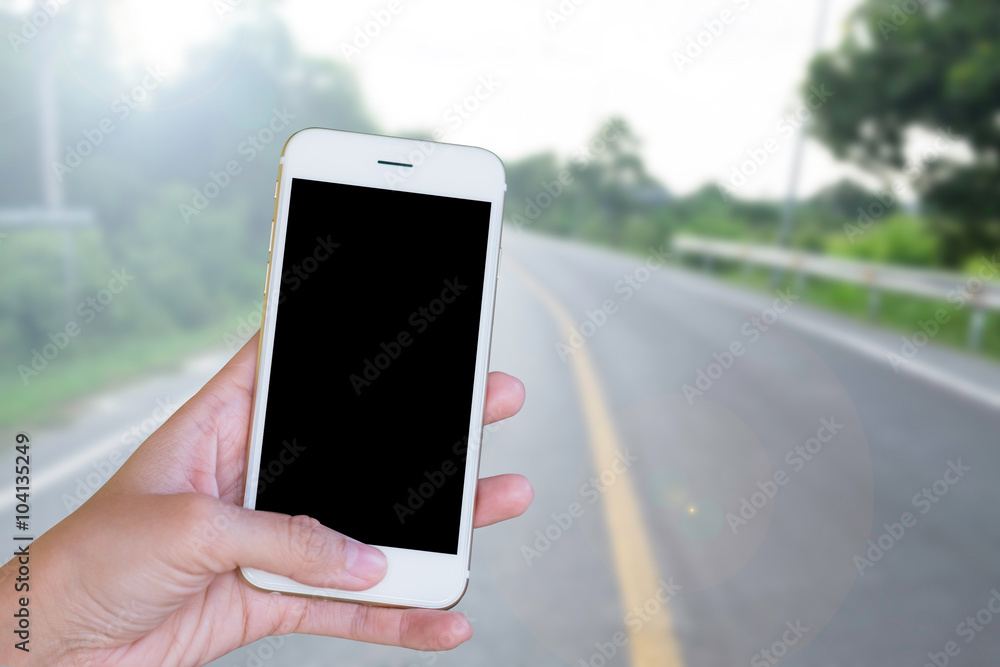 Hands woman are holding touch screen smart phone,tablet on blurred road nature background.