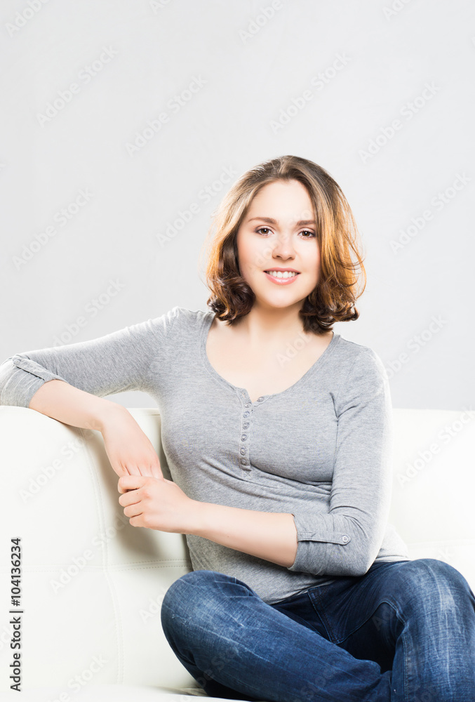Young and attractive girl sitting on a sofa at home.