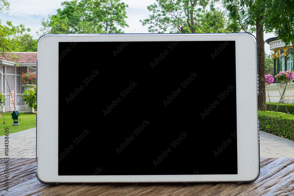 Tablet Computer on table with blurred the park garden nature background.