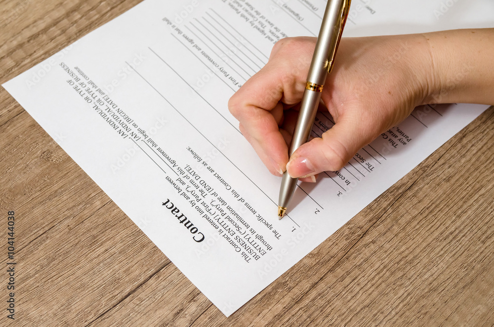 Obraz premium female hand signing a contract on desk