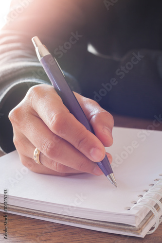 Woman hand with pen writing on notebook