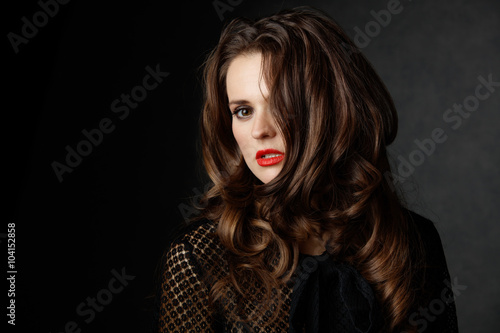 woman with curly brown hair covering half face  dark background