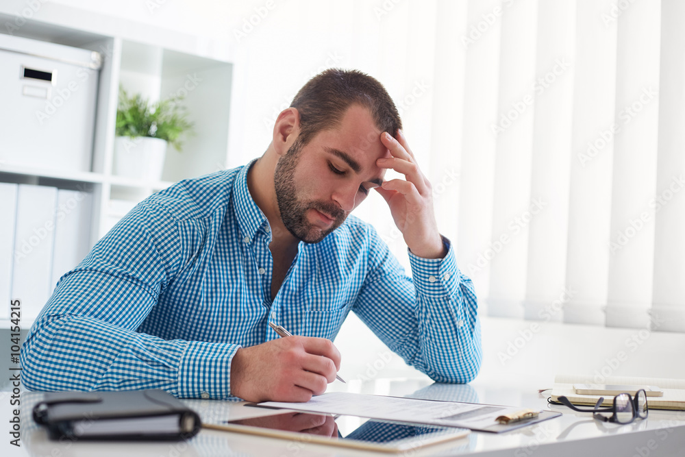 Pensive businessman signs a document Pensive businessman signs a document