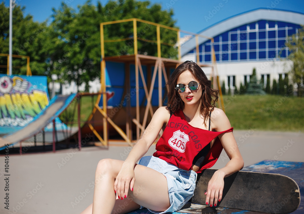 Hipster girl in the jeans and sunglasses with skateboard outdoor