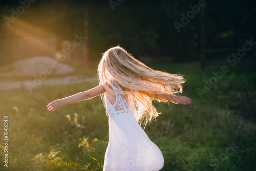 Portrait of a baby girl spinning in a field in sunset light, life style