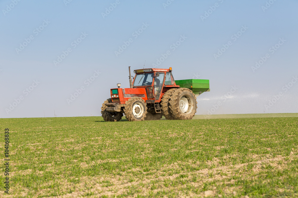 Farmer in tractor fertilizing wheat field at spring with npk Farmer in tractor fertilizing wheat field at spring with npk