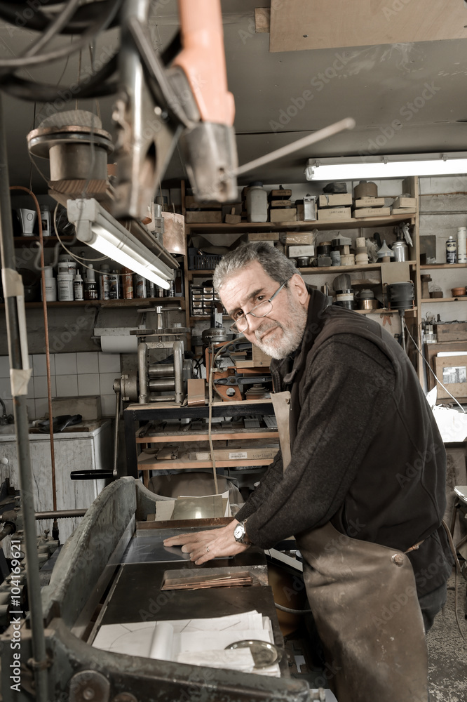 Master goldsmith working with silver-cutting a fine silver plate Master goldsmith working with silver-cutting a fine silver plate