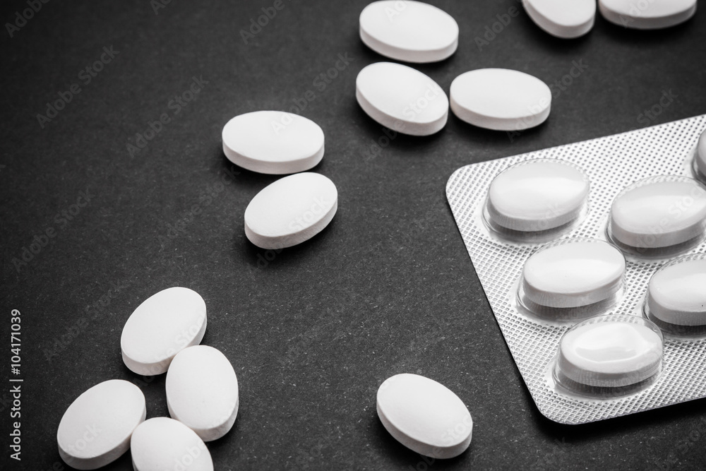 White pills on black surface. White pills on black surface.