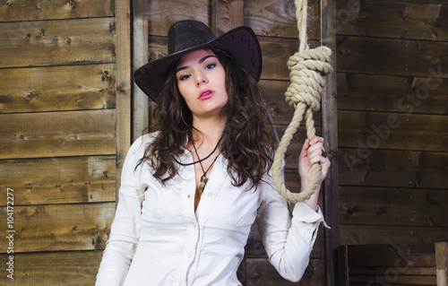 Billede på lærred the girl cowboy in the background of a wooden wall near the gallows