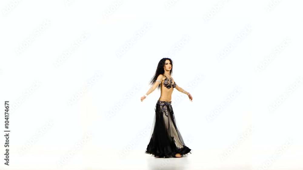 Beautiful young exotic belly dancer with long dark hair in unusual suit shaking her hips, on white Beautiful young exotic belly dancer with long dark hair in unusual suit shaking her hips, on white