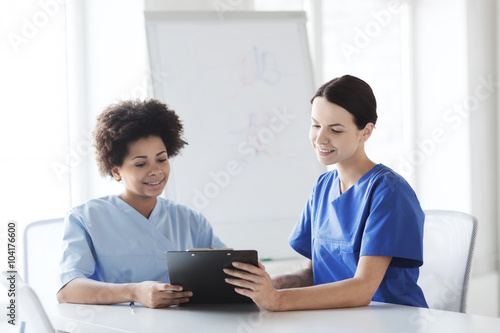 happy doctors with tablet pc meeting at hospital