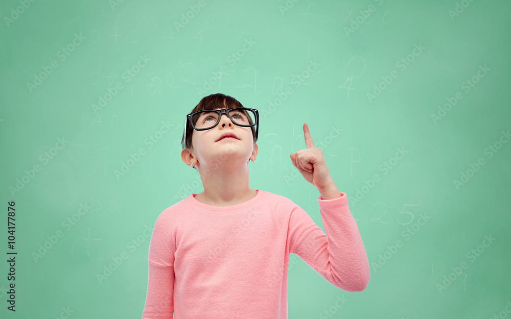 happy little girl in eyeglasses pointing finger up